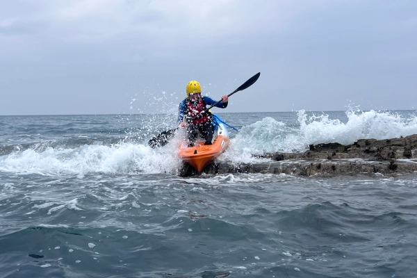 sea kayaking over rocks playing with the waves